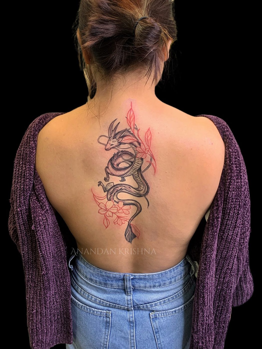 Fine-line dragon back tattoo with red floral detail at Divine Arts Tattoos.
