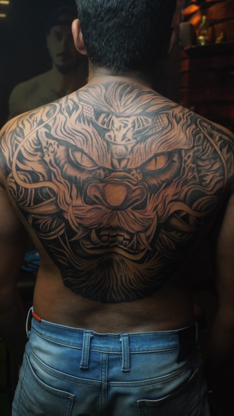 Large black-and-grey oriental lion back piece tattoo at Divine Arts Tattoos.